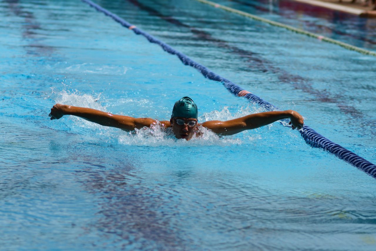 A man swimming in the pool with his arms out.