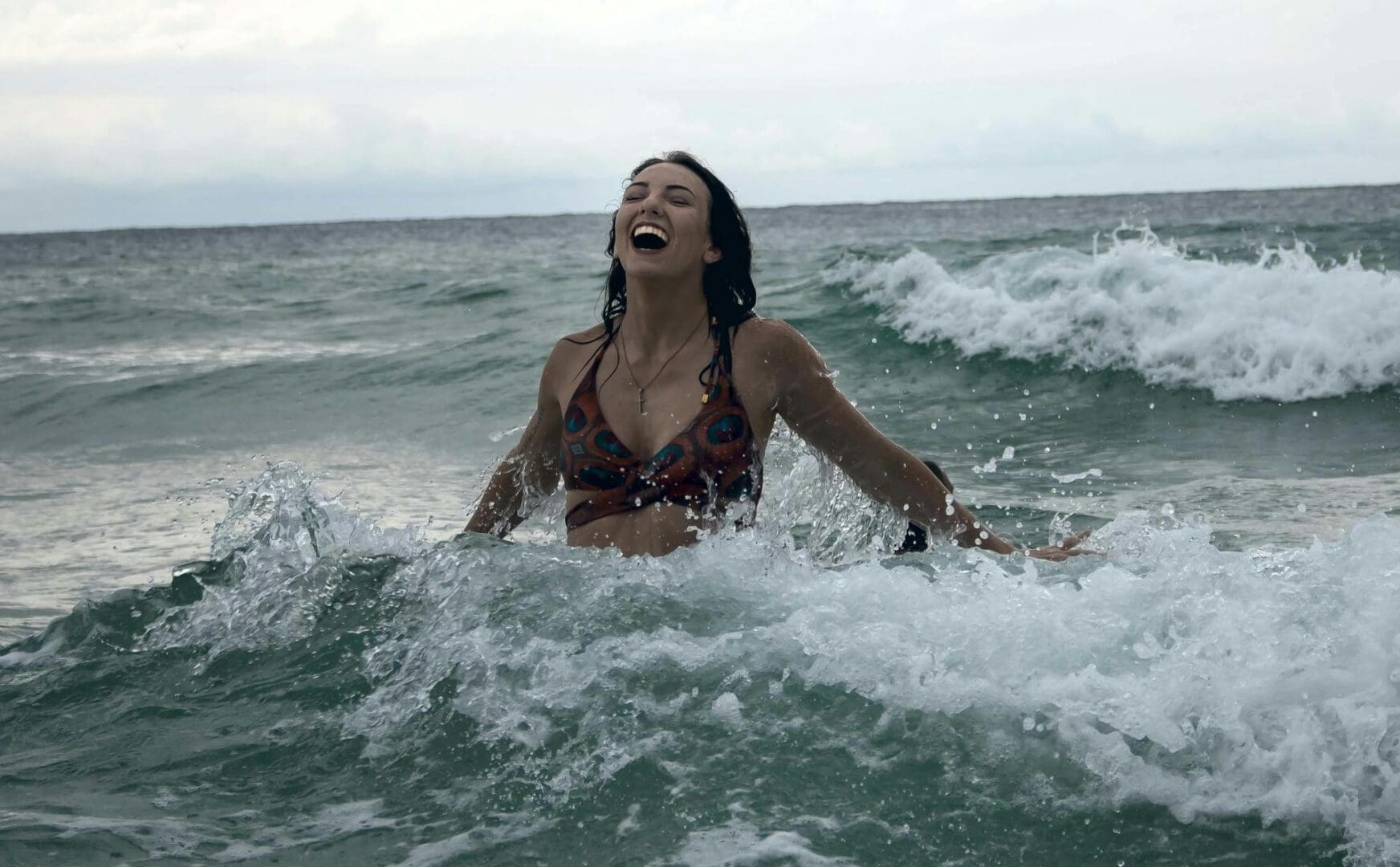 A woman in a bikini is splashing around in the ocean.